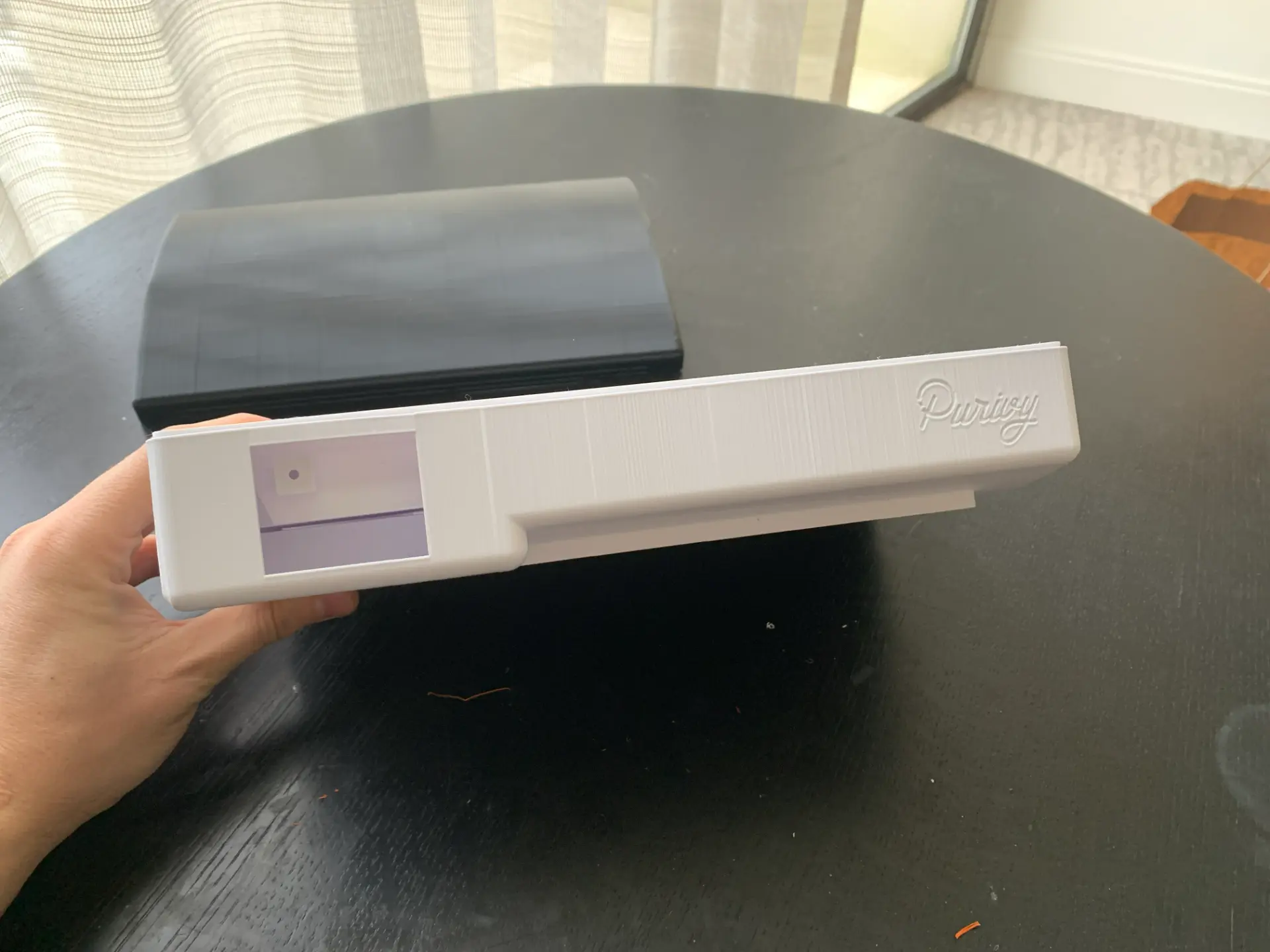 Early 3D printed Purivy enclosure prototype held closed, showing the embossed Purivy logo, front status window and parting line
