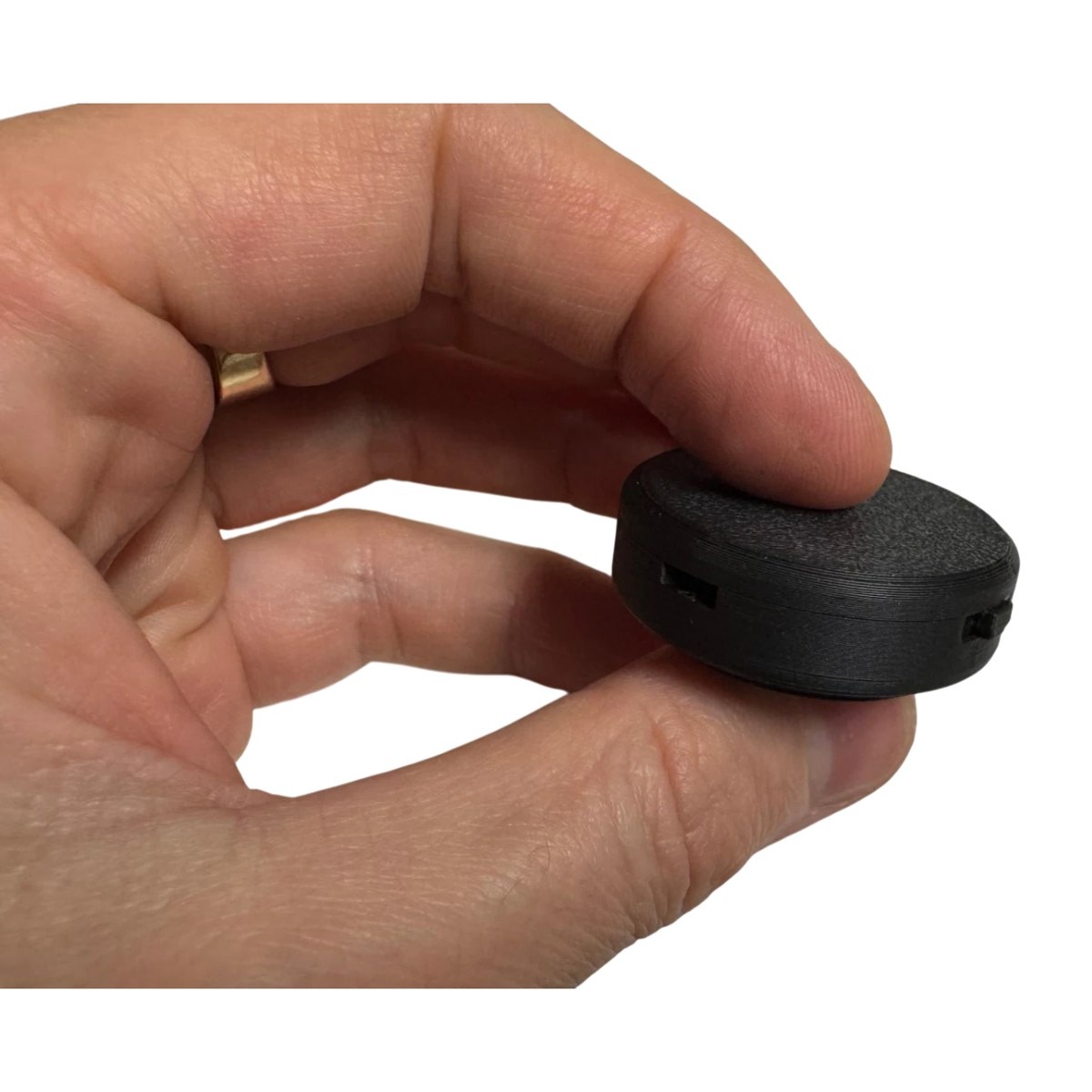 3D printed prototype of the QMS2GO voice recorder held between two fingers to show its size