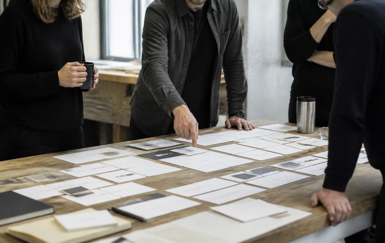 Product team reviewing printed candidate wordmarks spread across a workbench