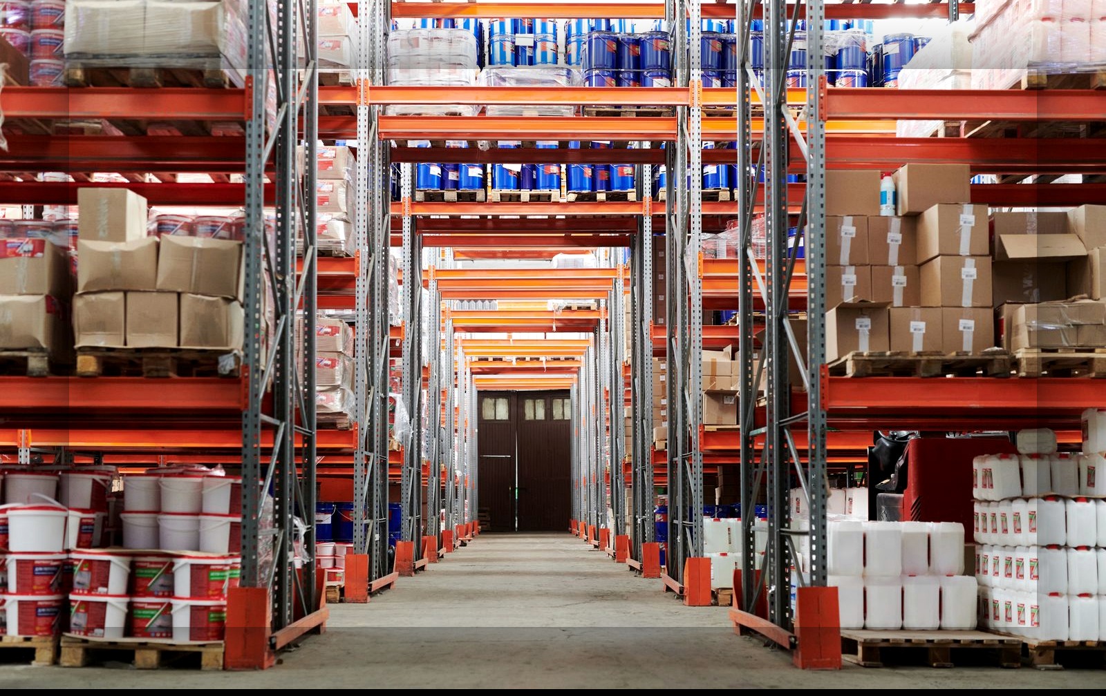 Industrial warehouse aisle with pallet racking and clear concrete floor representing environments where autonomous mobile robots navigate and move goods
