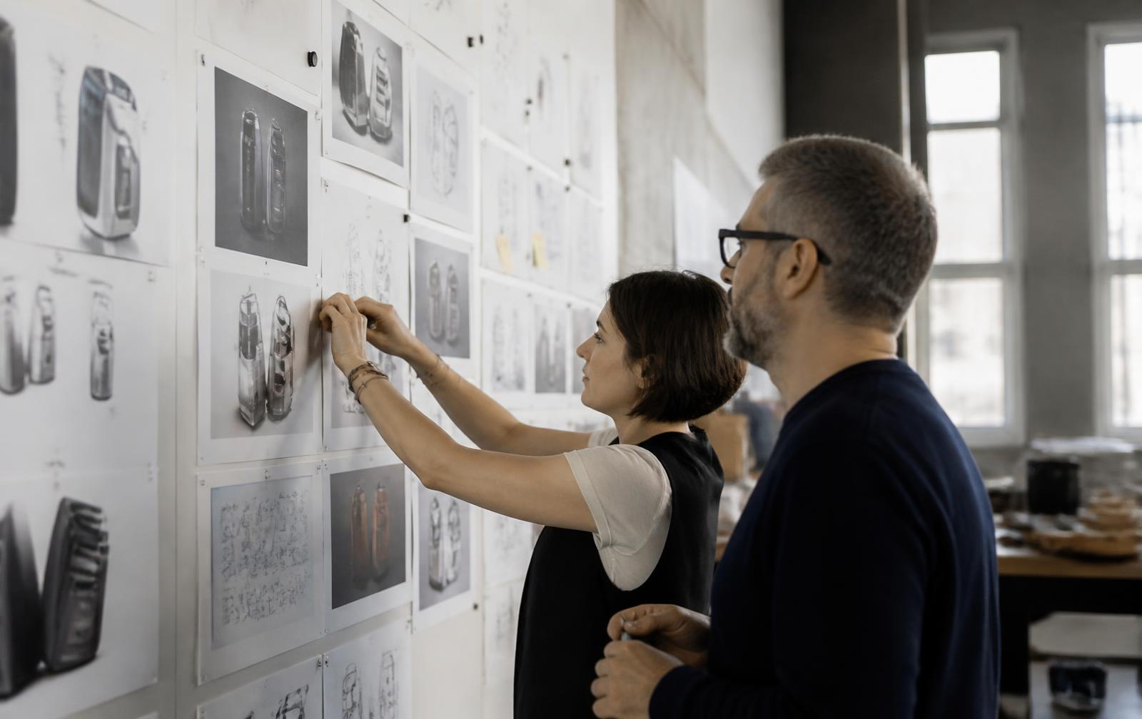 Designers pinning concept sketches to a wall board during a product definition workshop