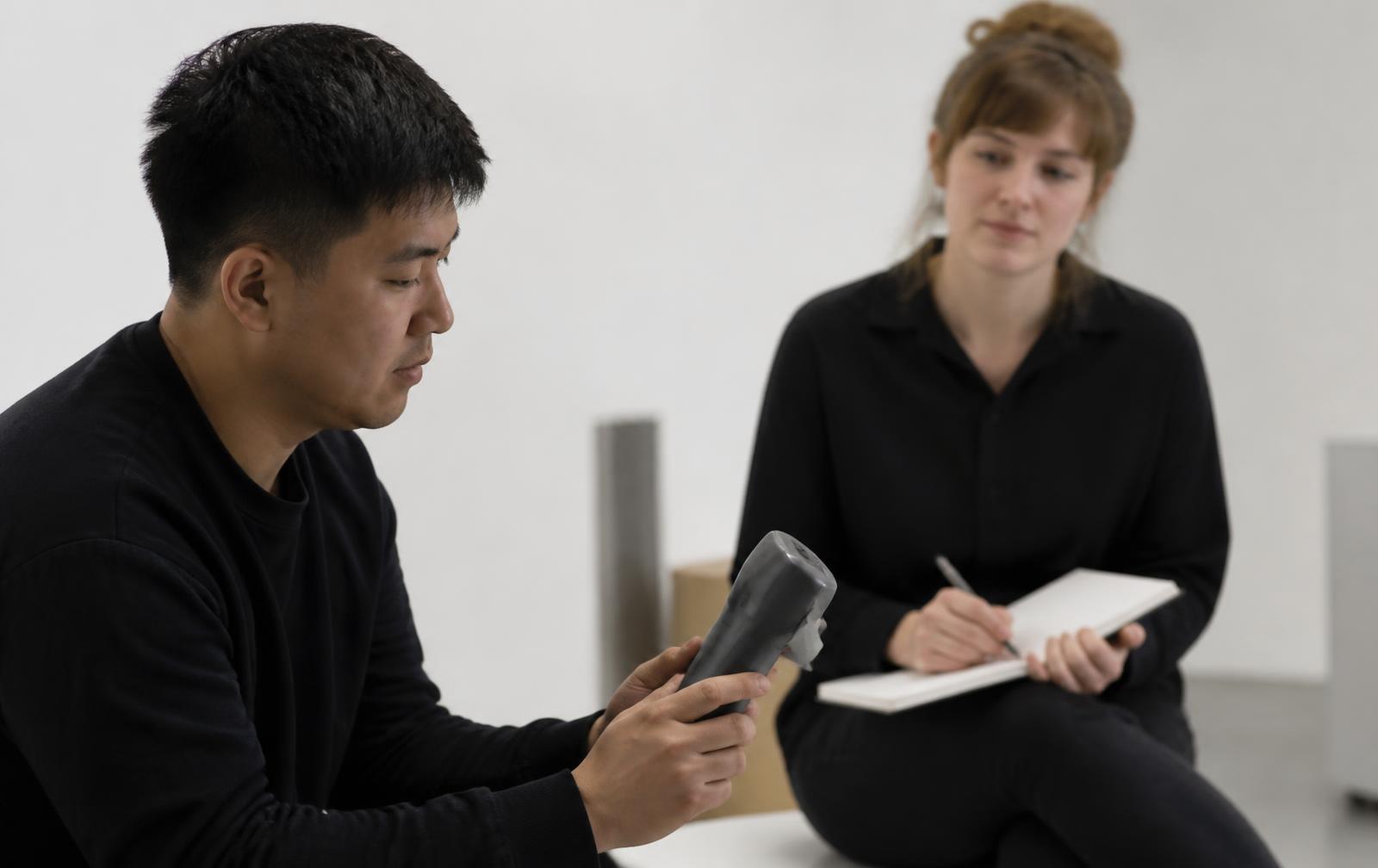Designer observing a first-time user handling a matte grey handheld prototype during an unassisted usability session