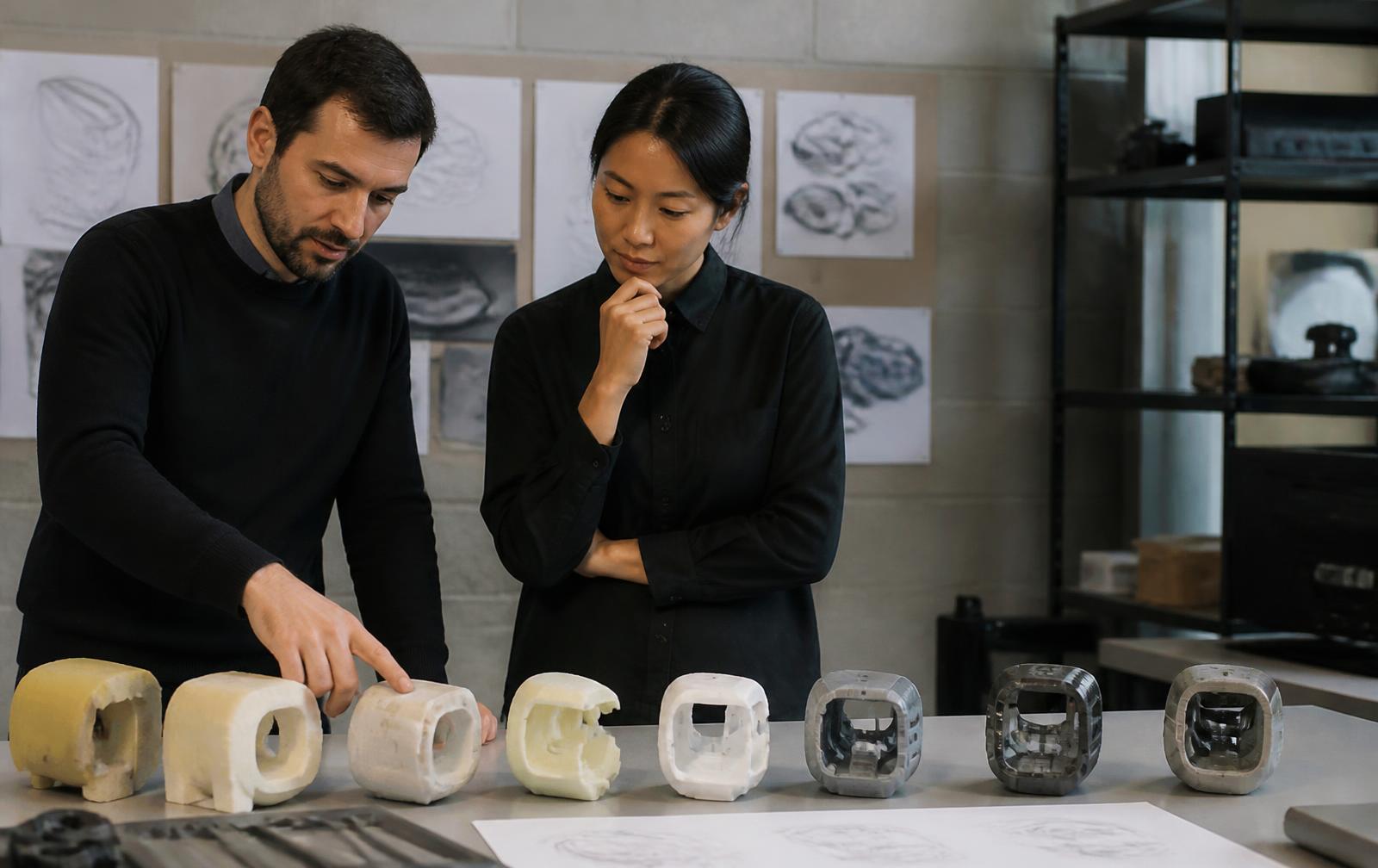 Designers reviewing a row of early-stage foam and 3D printed concept models on a workbench
