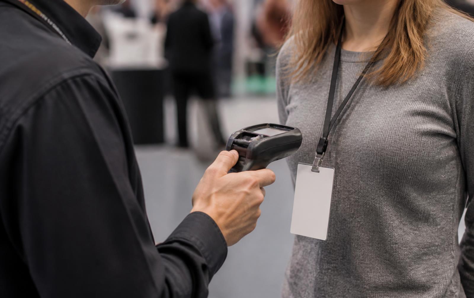 Exhibitor scanning a visitor badge with a handheld lead-capture scanner at a trade show booth