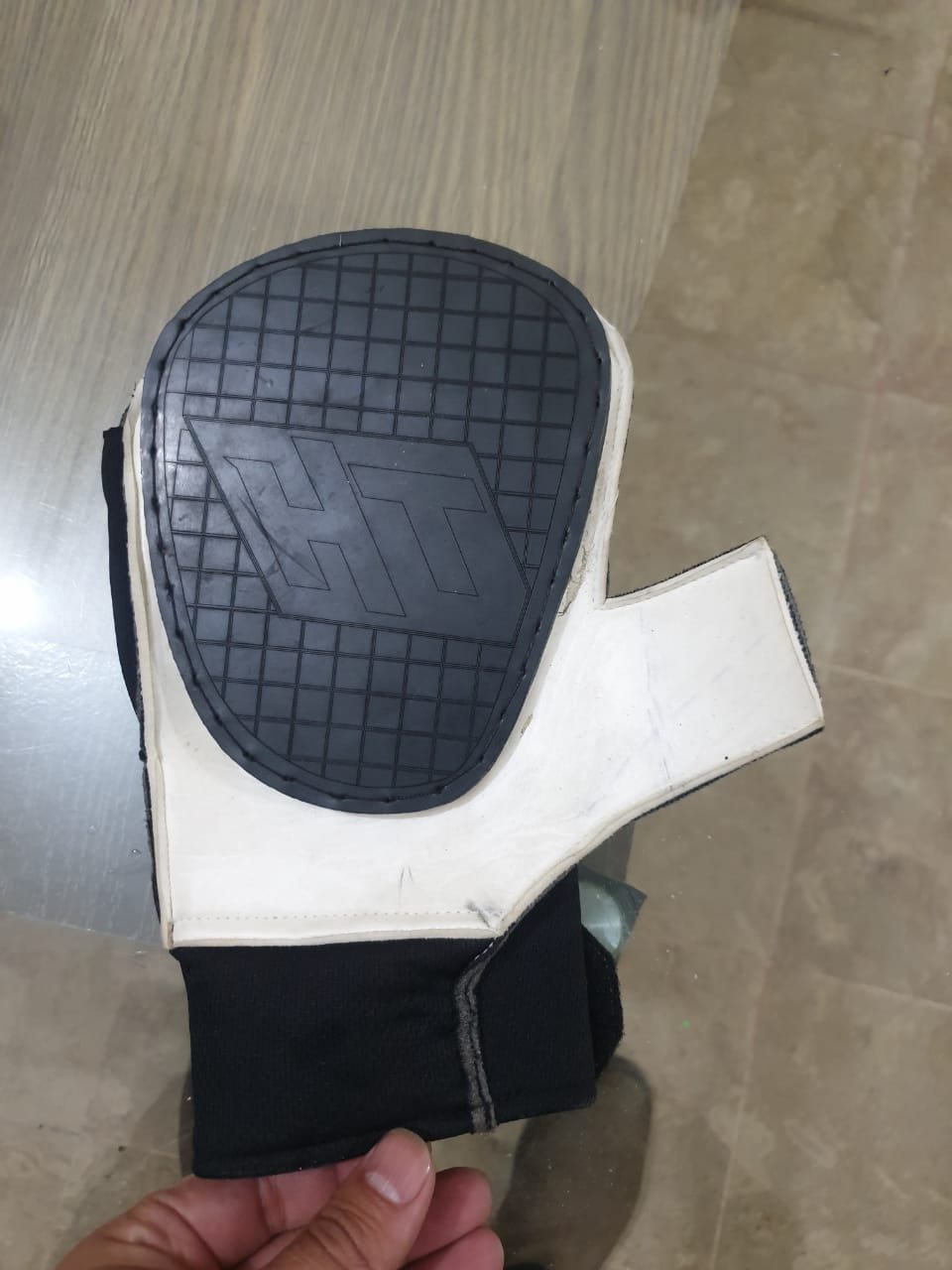 Early Hand Tennis glove prototype showing the black rubberized striking pad on a white glove body